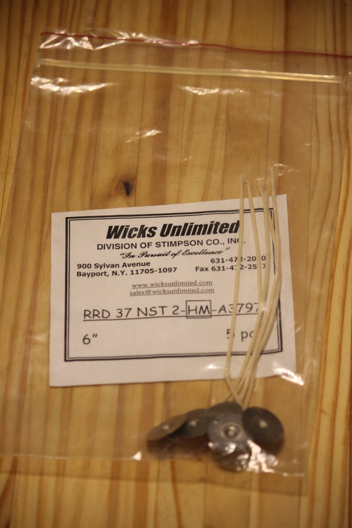 A clear plastic zip-top bag containing five six inch pre-tabbed wicks, placed on a light wood surface.
