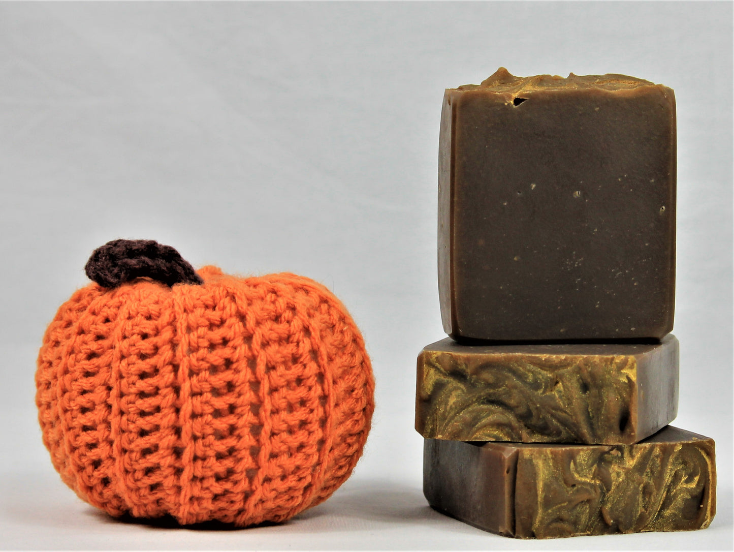 Stack of 3 deep brown soaps with gold embossed tops. Scented in pumpkin spice and pictured next to a crotched pumpkins made by Lauren at www evandroz.com