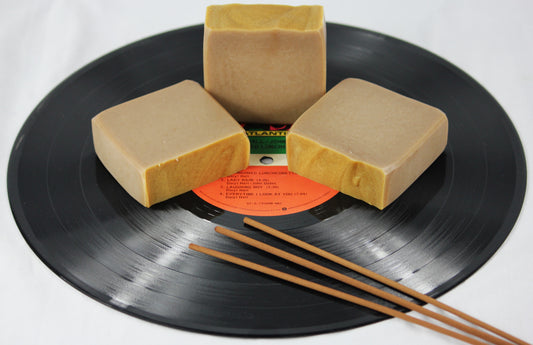 three bars of patchouli scented soap on a vinyl record, accented with incense sticks.