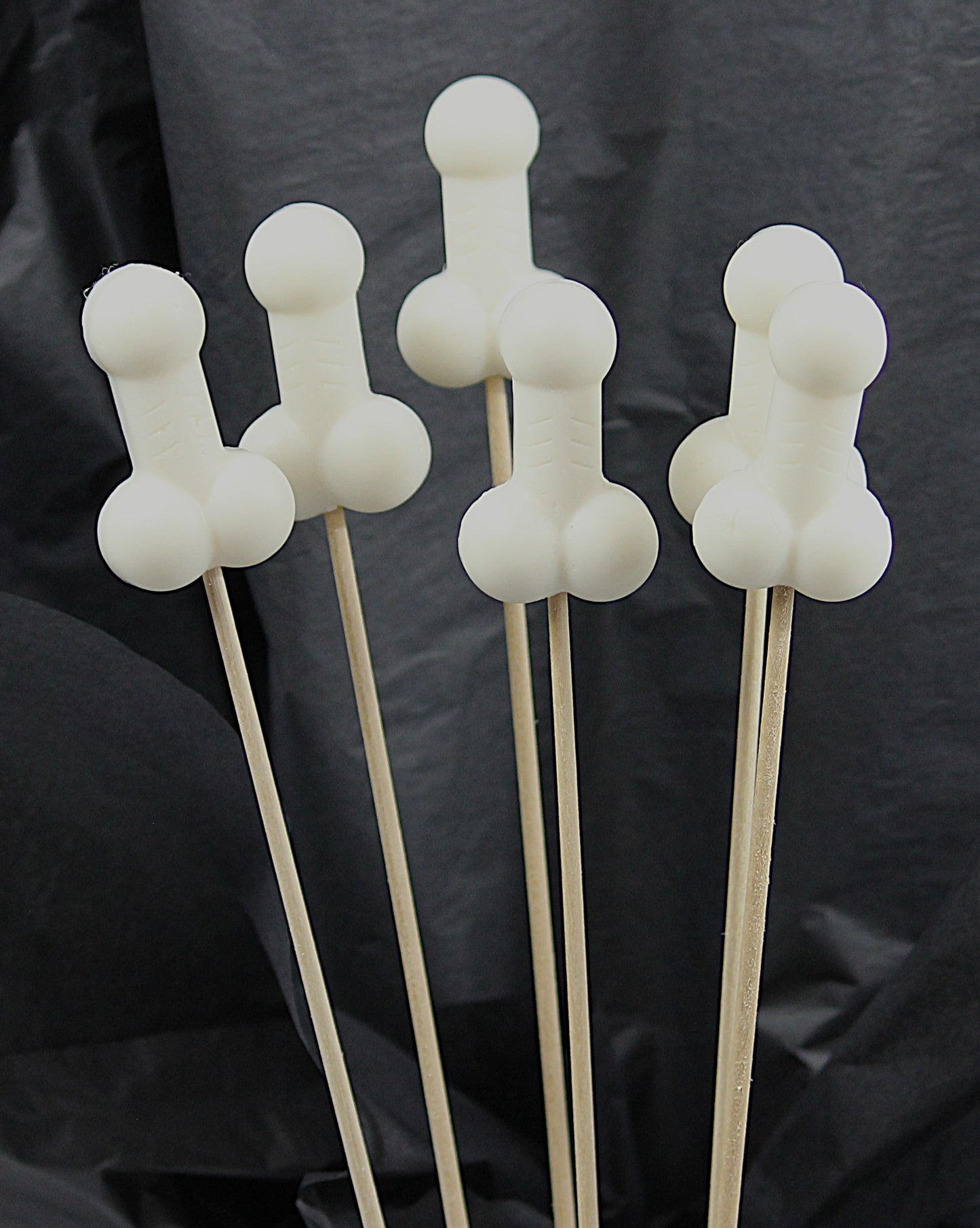 A bouquet of six white soap penises against a black backdrop.