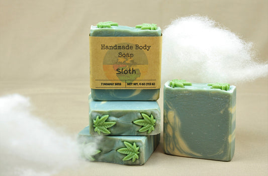 four 4oz homemade soap bars, named "Sloth".  Bars are a beautiful sky blue color, with swirls of white and topped with 2 soap embeds shaped like cannabis leaves.