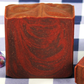 Reddish-brown soap bar with a textured surface on a checkered background