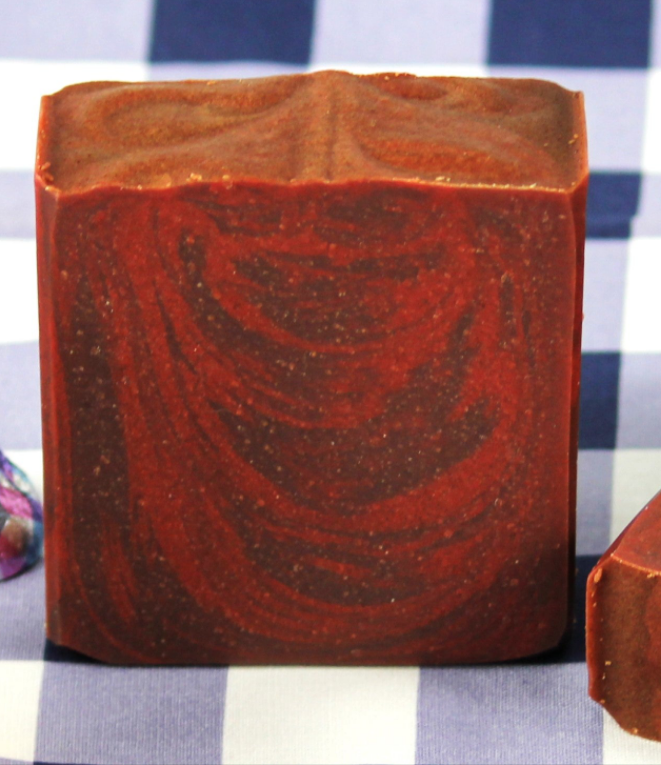 Reddish-brown soap bar with a textured surface on a checkered background
