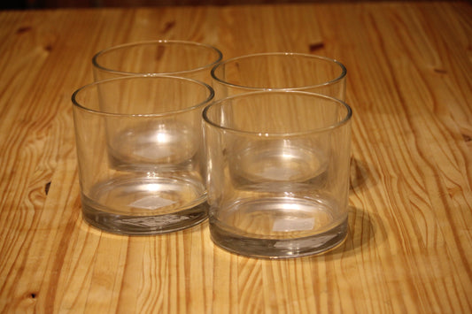 Four clear glass tumblers arranged on a light brown wooden tabletop.