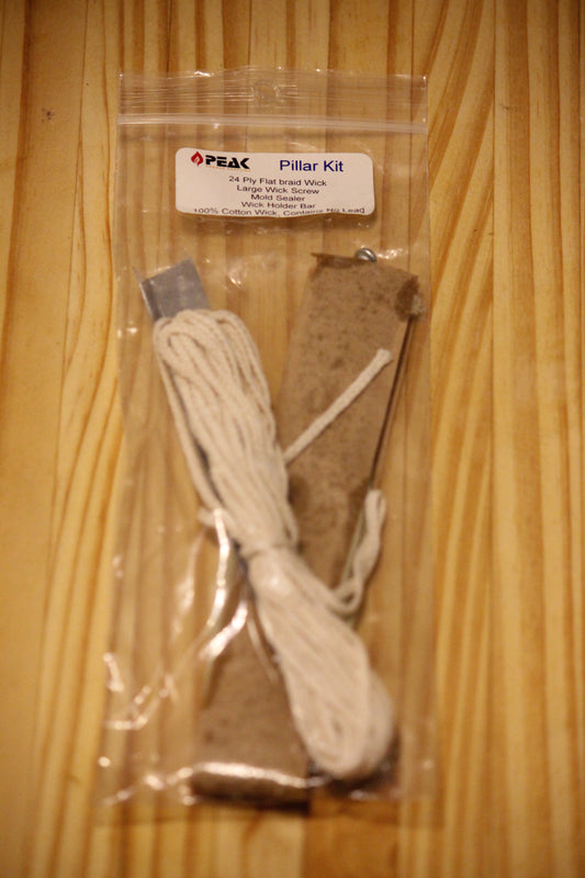 A packaged 'Pillar Kit' by Peak, containing a bundle of cotton wick and accessories, sealed in a clear plastic bag and placed on a wooden surface.