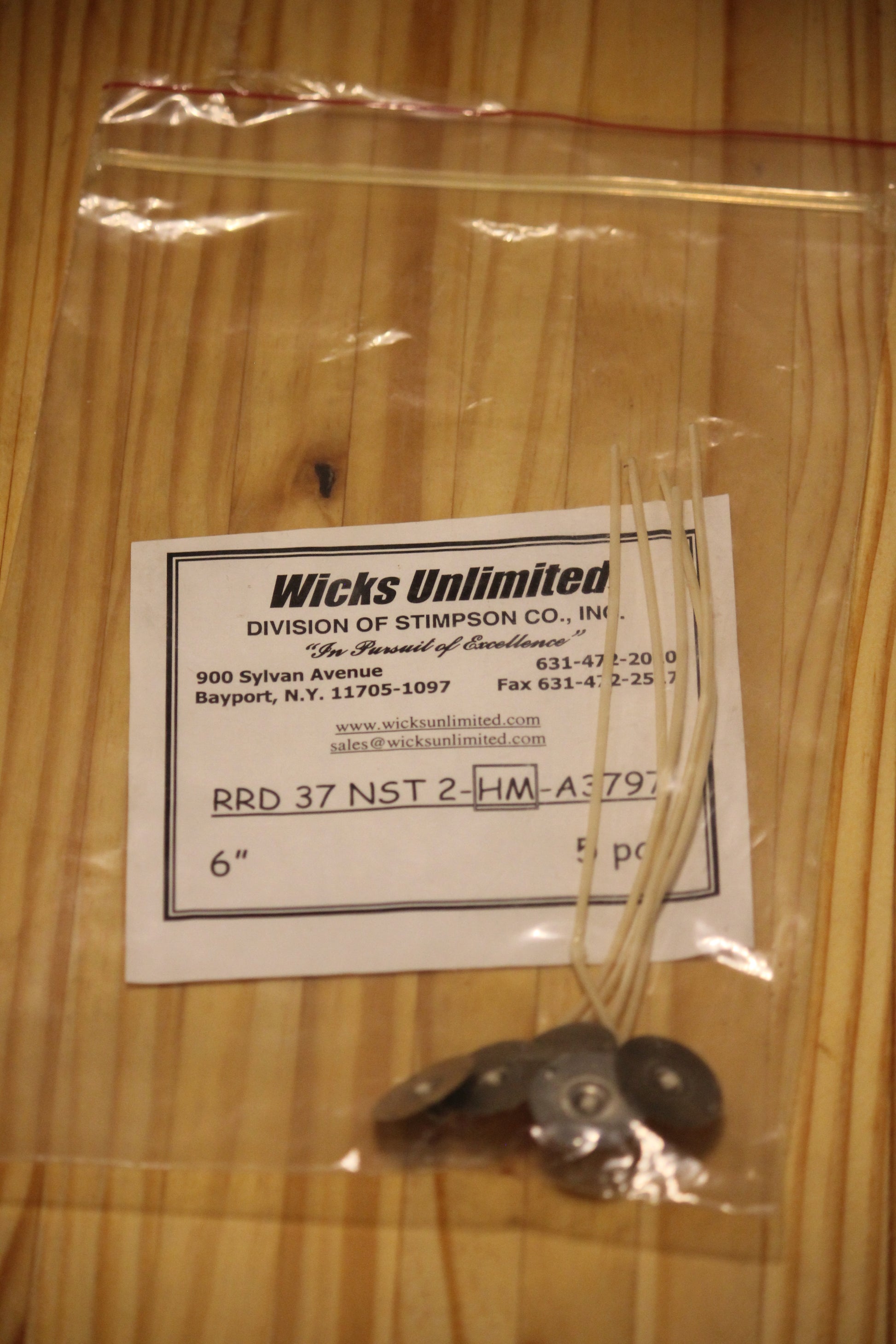 A clear plastic zip-top bag containing five six inch pre-tabbed wicks, placed on a light wood surface.