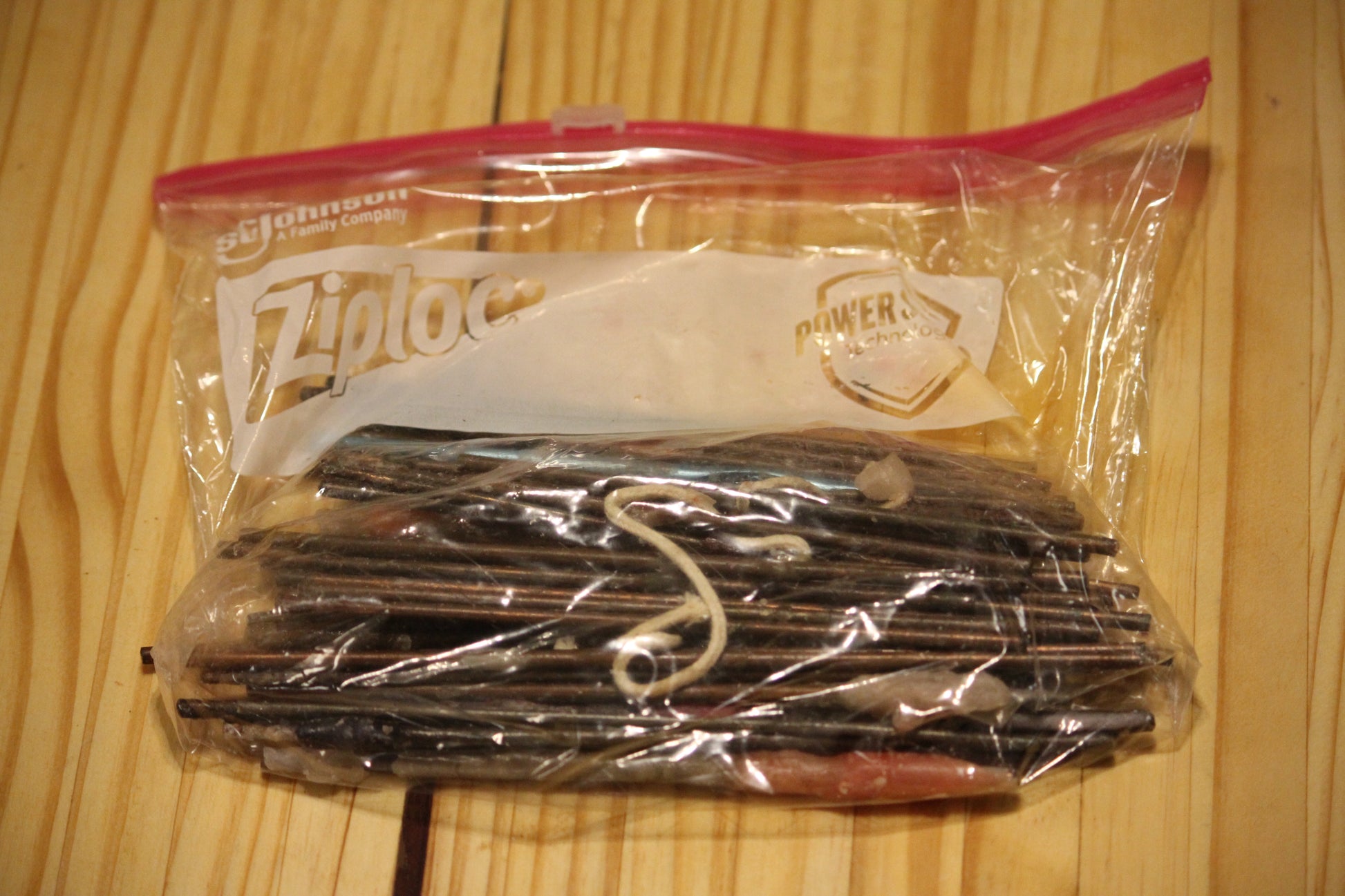 A clear plastic zip-top bag containing metal wick pins. 