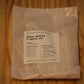 A small clear plastic bag containing white wick material, with a white label reading 'OPAL WHITE X WICK .02' and 'THE WOODEN WICK CO.