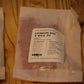 A clear plastic bag containing red wood wicks, with a white label reading 'THE WOODEN WICK CO. CRIMSON RED X WICK .