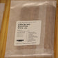 A clear plastic bag containing wood wicks, Crackling Booster Wick .04, with a white product label, resting on a light-colored wooden surface.