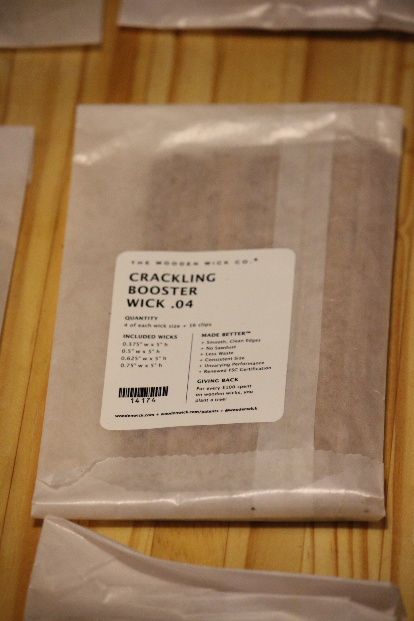 A clear plastic bag containing wood wicks, Crackling Booster Wick .04, with a white product label, resting on a light-colored wooden surface.
