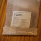 A clear plastic bag containing natural wood wick material, with a white label reading 'THE WOODEN WICK CO. NATURAL X WICK .