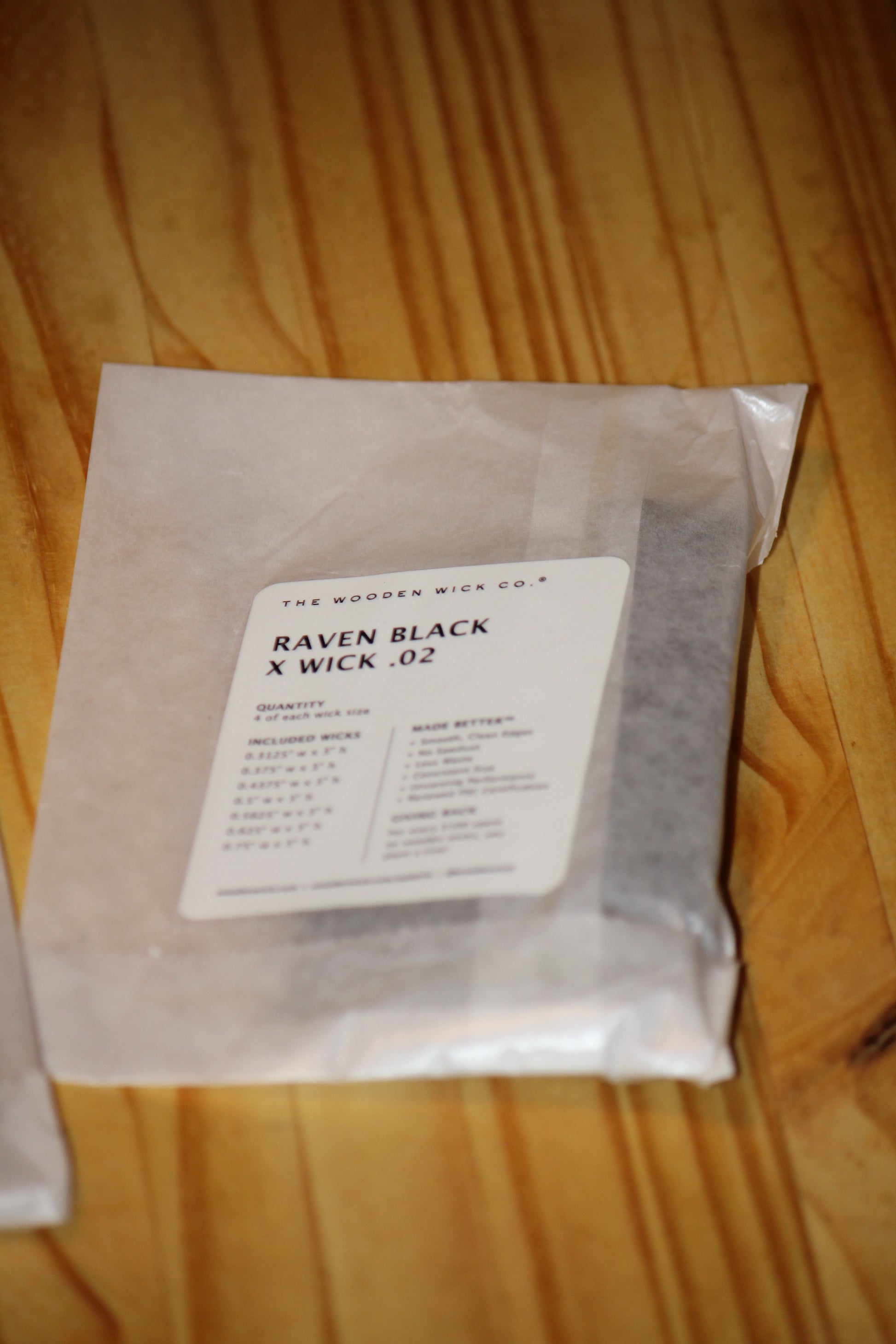 A sealed translucent pouch labeled RAVEN BLACK X WICK .
