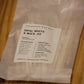 A clear plastic bag containing white wood wicks with a white paper label reading 'THE WOODEN WICK CO. OPAL WHITE X WICK .