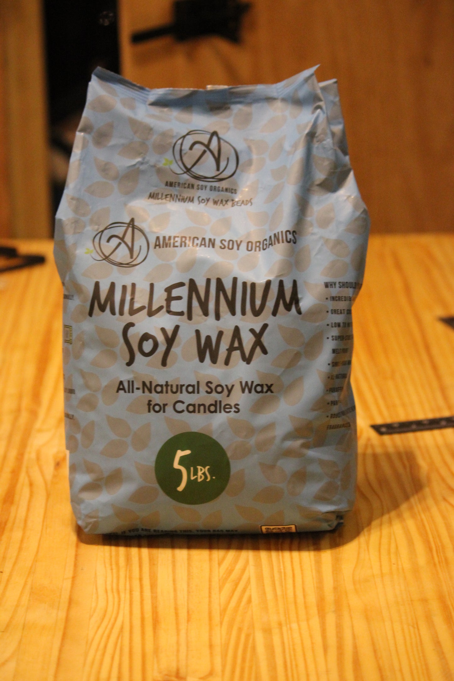 A 5 lb bag of American Soy Organics Millennium Soy Wax for candles, standing on a light wood tabletop.