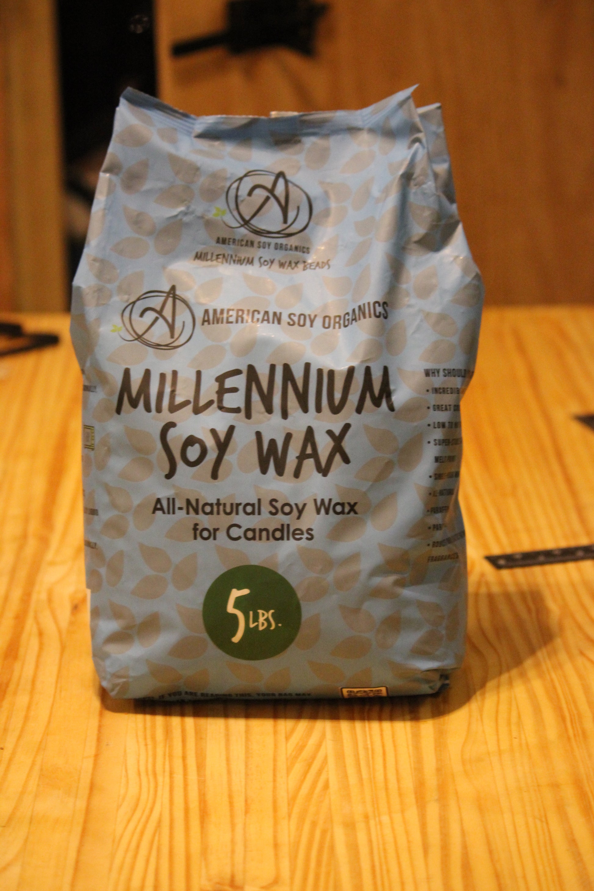 A 5 lb bag of American Soy Organics Millennium Soy Wax for candles, standing on a light wood tabletop.