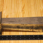 A metal pillar candle mold, shown on a light wood grain surface next to a black ruler for scale.