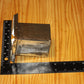 A metal square pillar mold, shown on a light wood grain background with a black ruler for scale.