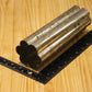 A metal flower shaped pillar mold, shown on a light wood grain background with a black ruler for scale.