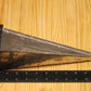 A metal pyramid pillar mold, shown on a light wood grain background with a black ruler for scale.