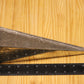 A metal pyramid pillar mold, shown on a light wood grain background with a black ruler for scale.