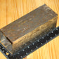 A metal square pillar mold, shown on a light wood grain background with a black ruler for scale.