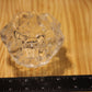 A small clear faceted glass candle holder placed on a wooden surface with a black ruler visible along the left and bottom edges for scale.