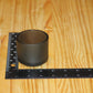 A small matte black cylindrical candle holder placed on a wooden surface next to a black ruler for scale.