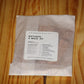 A clear plastic bag containing wood wicks with a white paper label reading 'THE WOODEN WICK CO. NATURAL X WICK .