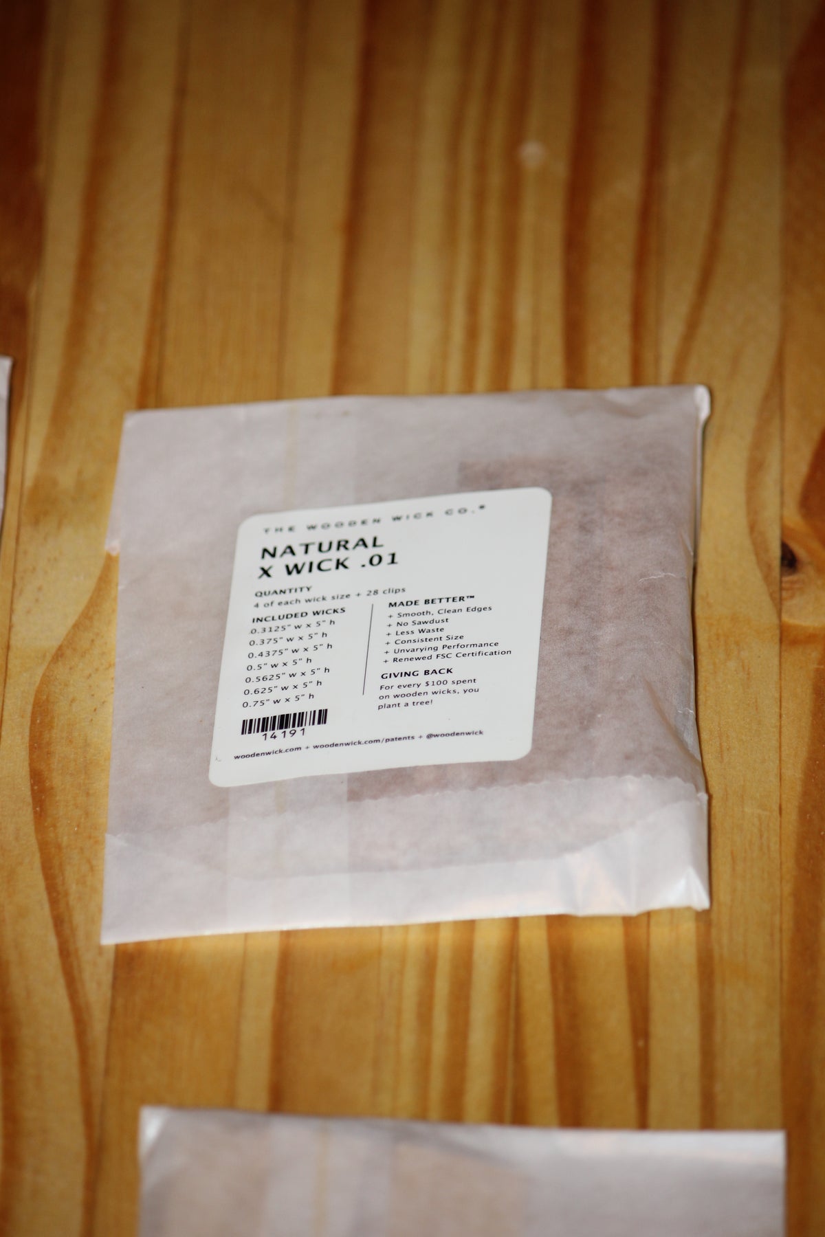 A clear plastic bag containing wood wicks with a white label reading 'THE WOODEN WICK CO. NATURAL X WICK .