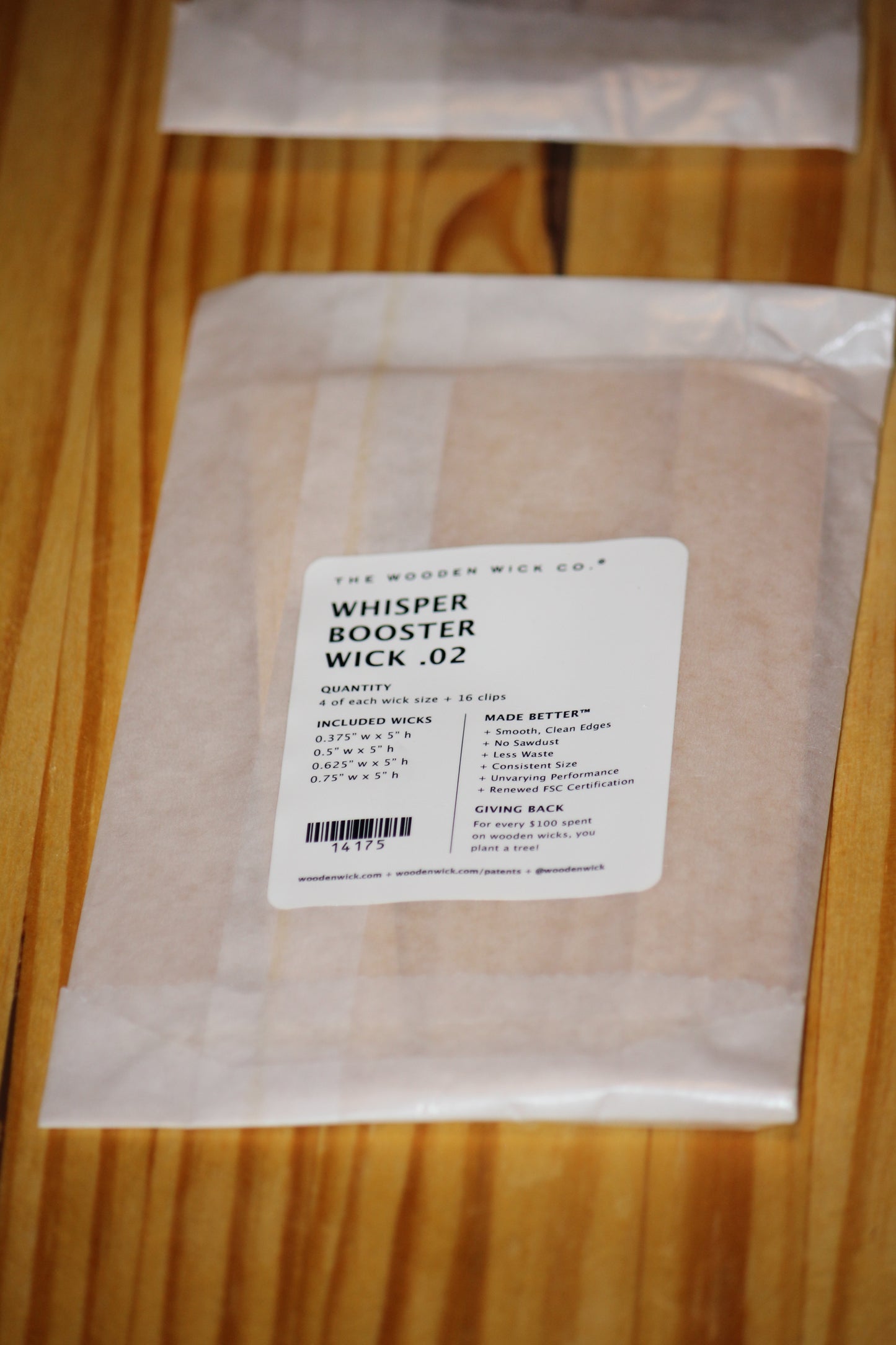 A clear plastic bag containing wooden wicks, sealed with a white label that reads 'THE WOODEN WICK CO. WHISPER BOOSTER WICK .