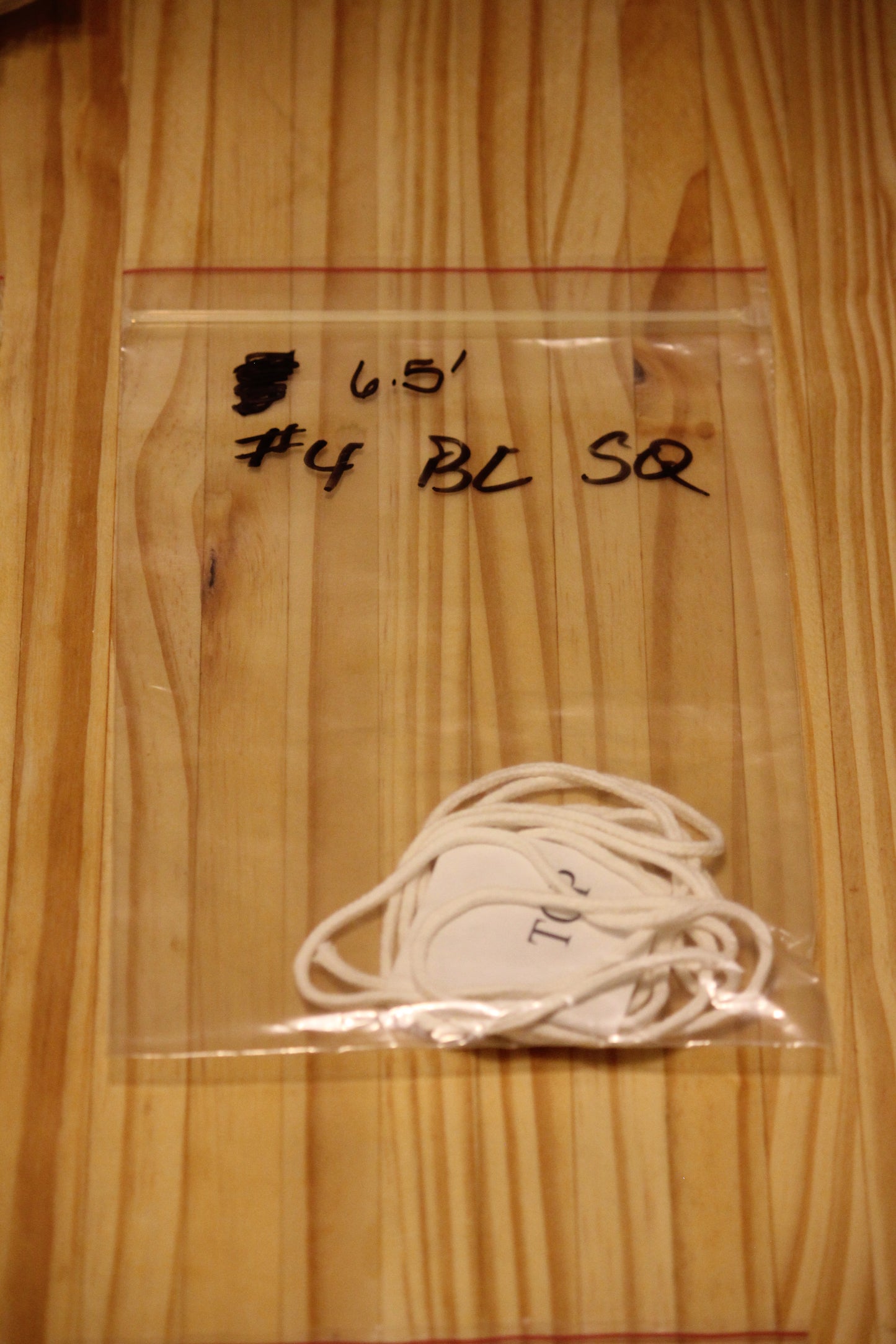 A clear plastic zip-top bag containing a bundle of white wicking material, placed on a light wood surface. 