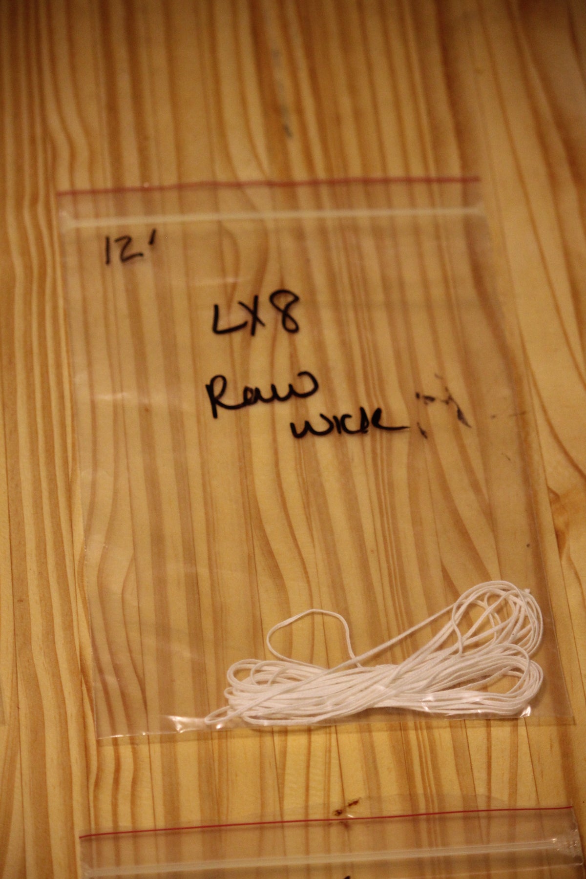 A clear plastic zip-top bag containing a bundle of white wicking material, placed on a light wood surface. 