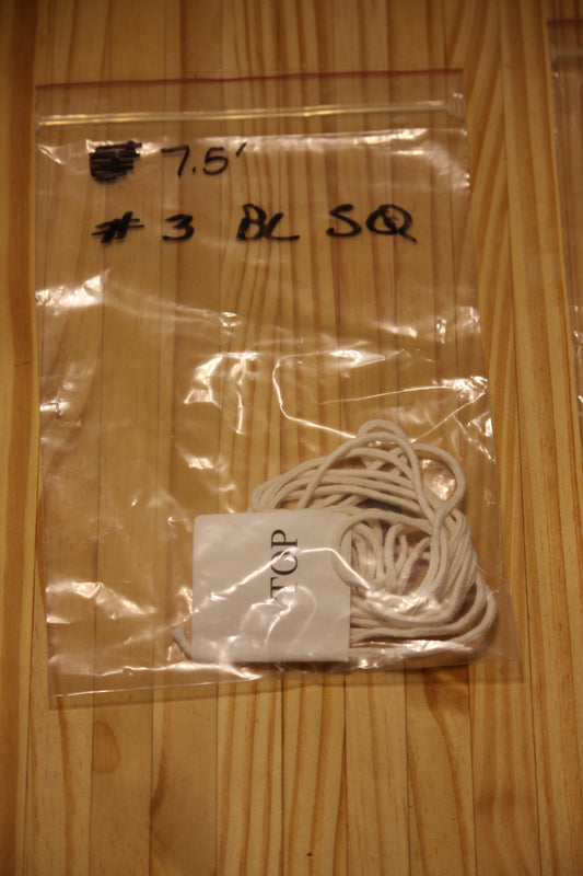 A clear plastic zip-top bag containing a bundle of white wicking material, placed on a light wood surface. 