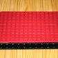 A red rectangular silicone mold tray with heart cavities, shown on a light wood surface next to a black measuring ruler to indicate size.