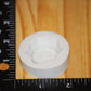A white circular silicone mold of a wooden stump, shown on a wooden surface next to a black ruler for scale.