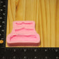 A pink silicone mold of tree branches and sticks, shown on a light wood surface next to a black ruler for scale.