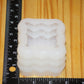 A white silicone mold with a textured, pumkpin pattern, shown next to a black measuring ruler on a light wood grain background.