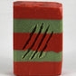 Red and green striped soap bar with 4 slash marks across front