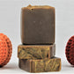 Stack of 3 deep brown soaps with gold embossed tops. Scented in pumpkin spice and surrounded by crotched pumpkins made by Lauren at www evandroz.com