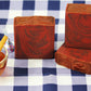 Three bars of soap with a cup of cider on a checkered tablecloth