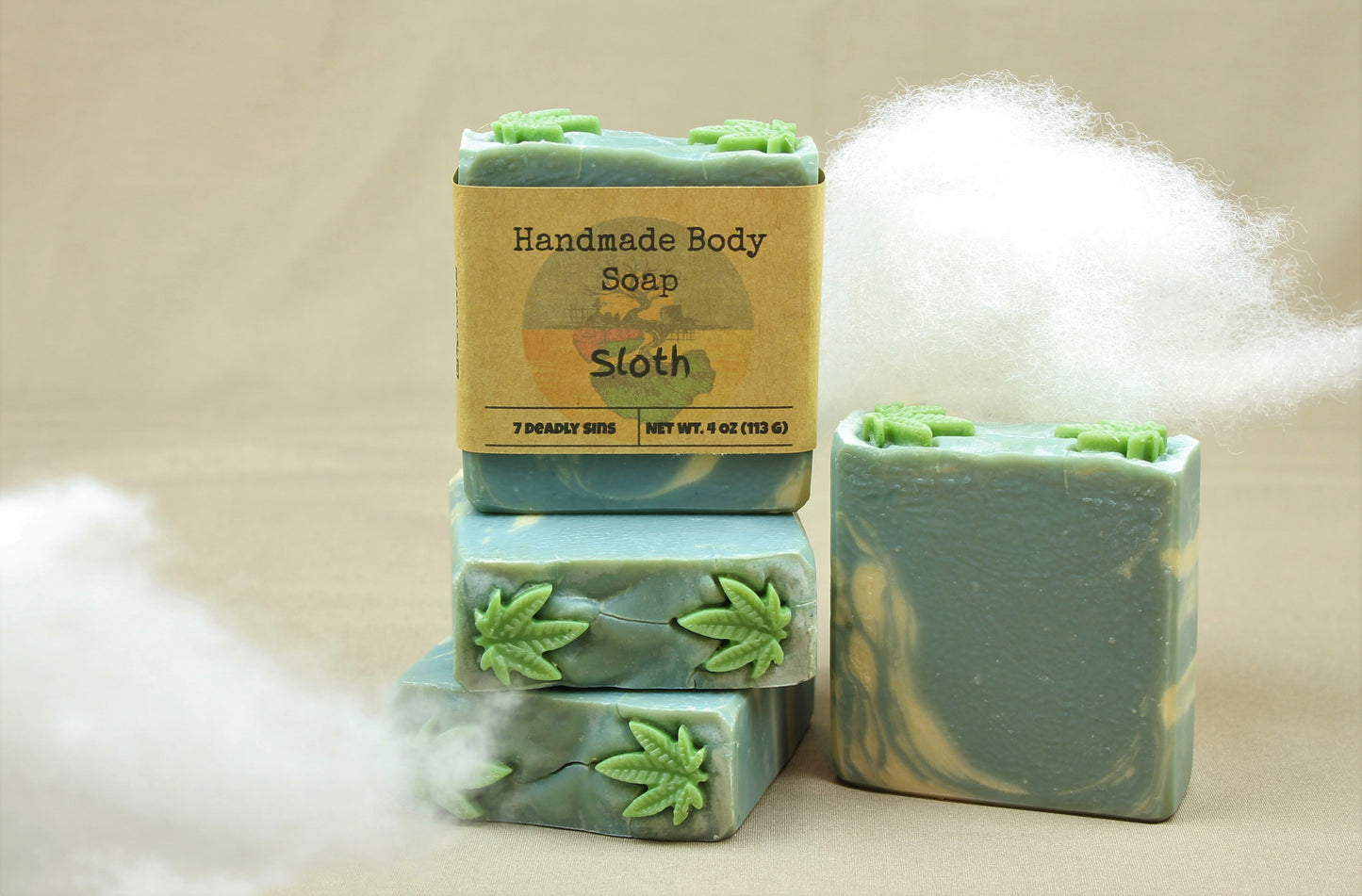 four 4oz homemade soap bars, named "Sloth".  Bars are a beautiful sky blue color, with swirls of white and topped with 2 soap embeds shaped like cannabis leaves.  