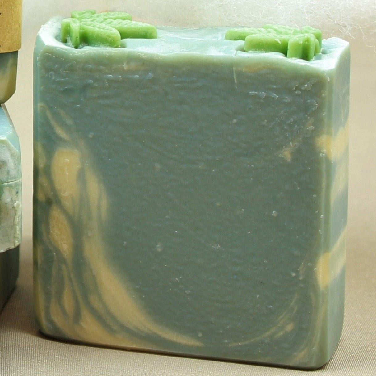 Pictured handmade body soap bar, Sloth. Shown without label. Soap is sky blue and white, with green cannabis leaf shaped soap on top, and scented in cannabis flower.
